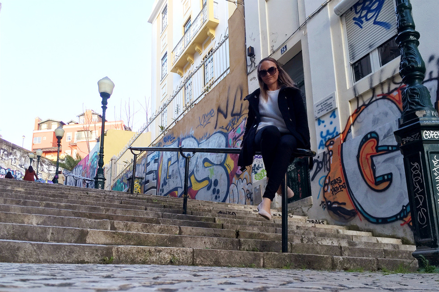 Sitting in front of colourful street art and graffiti on the Calcada do Lavra stairs, Lisbon, Portugal - Calçada do Lavra street art.