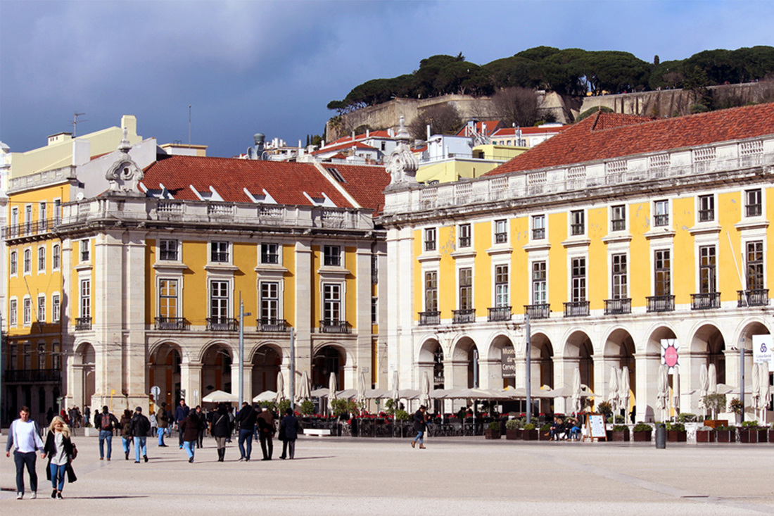 Traditional Portuguese yellow painted buildings in Praça do Comércio, overlooked by São Jorge Castle/ Castelo de São Jorge - Pombaline-Baixa, Lisbon - Portugal.