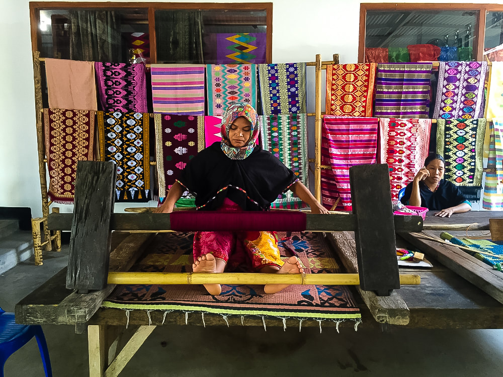 Lombok: Sukarara Weaving Village - A woman working using a traditional loom at the Patuh Art Shop.