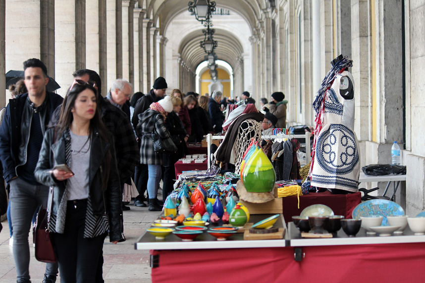 People shopping under the arcade at the Praca do Comercio handicraft market, Lisbon, Portugal.