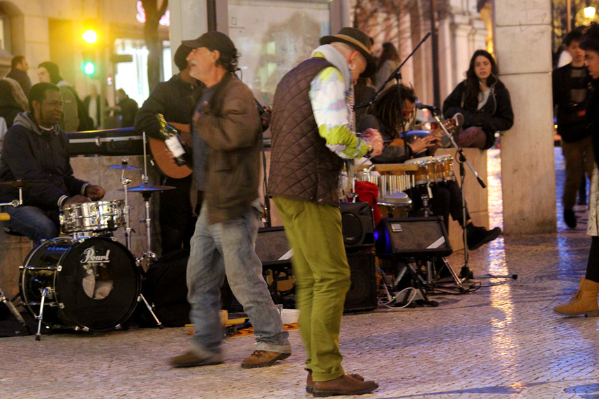 Musicians and street performers busking while people dance to the music outside of Café a Brasileira on Rua Garrett, Lisbon at night, Portugal.