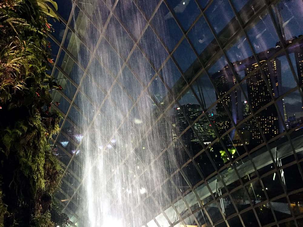 The Cloud Forest waterfall and dome, with Marina Bay Sands in the background, inside the Cloud Forest at Gardens by the Bay in Singapore.