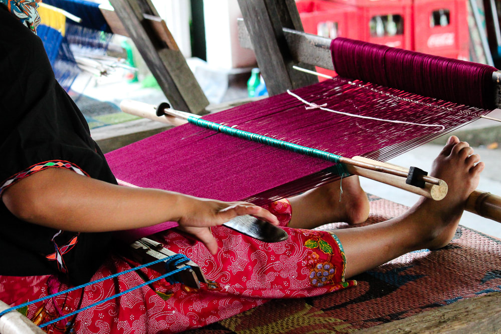 Lombok: Sukarara Weaving Village - A woman working using a traditional loom at the Patuh Art Shop.
