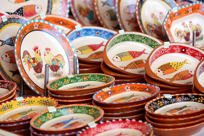 Close up of bowls with portuguese cockerels and fish painted on them at the Praca do Comercio handicraft market, Lisbon, Portugal.