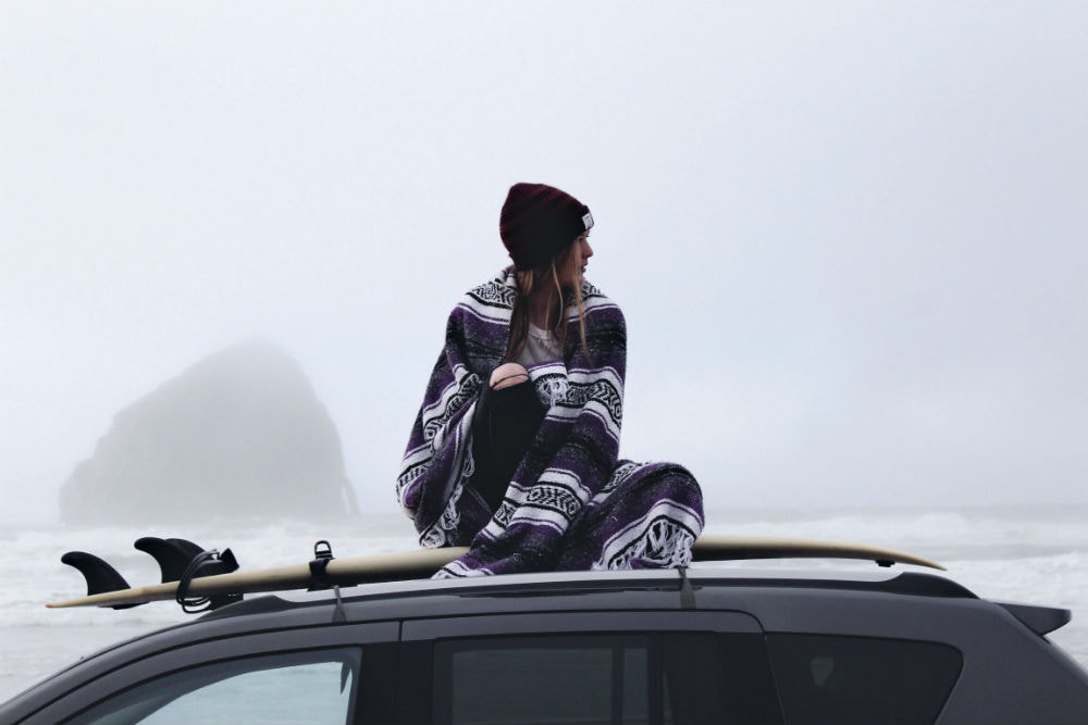 Why No Rules Is the Best Option When Going on a Road Trip. Girl with surfboard by the ocean.