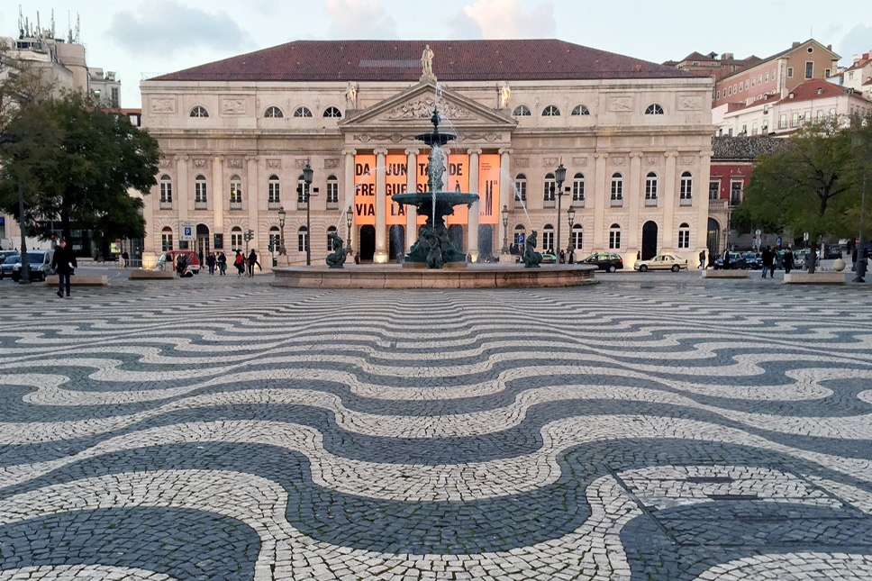 Portuguese pattern pavement, a bronze fountain and the National Theatre D.Maria II (Teatro Nacional D.Maria II) in Pedro IV/ Rossio Square, Lisbon, Portugal.
